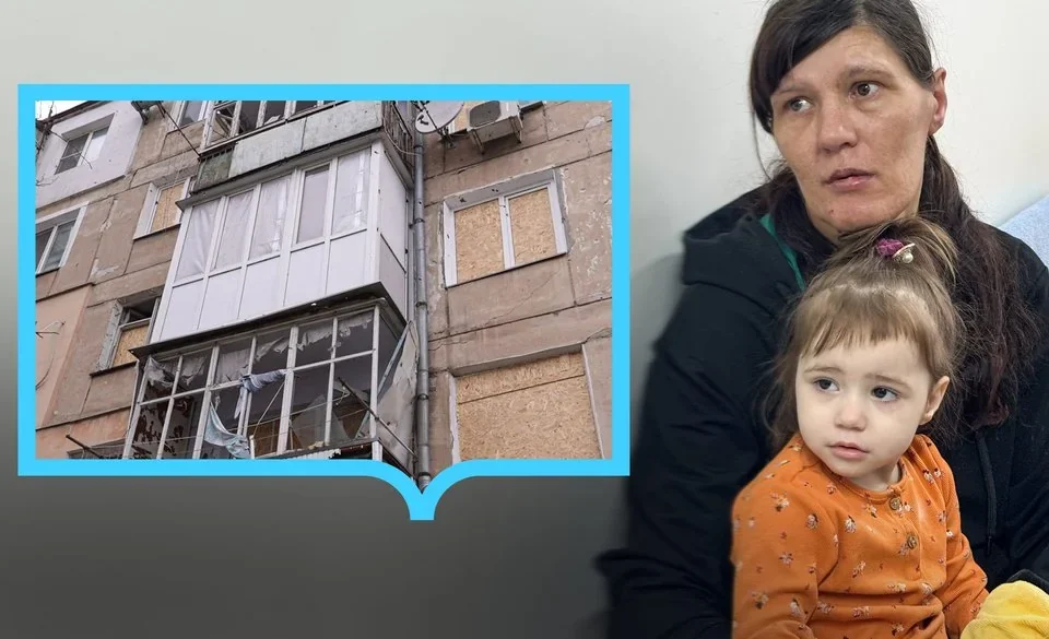 Жінка з маленькою дівчинкою і фото пошкодженого будинку з забитими вікнами