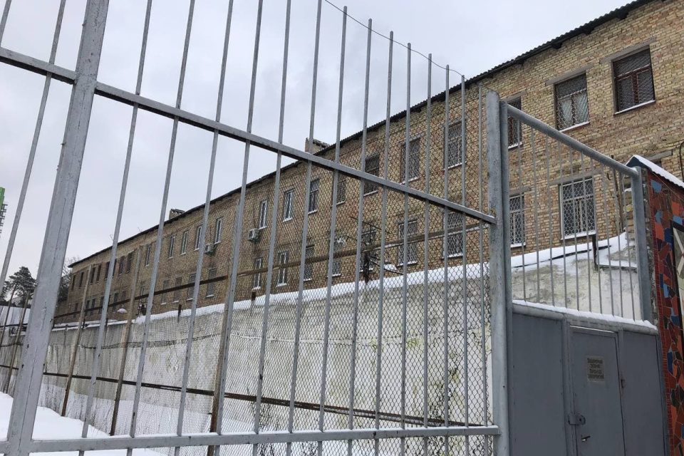 Цегляна будівля за металевою ґратчастою огорожею взимку